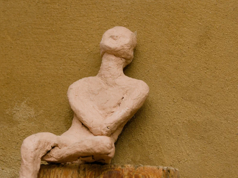 Tonfigur, die an einer Wand lehnt